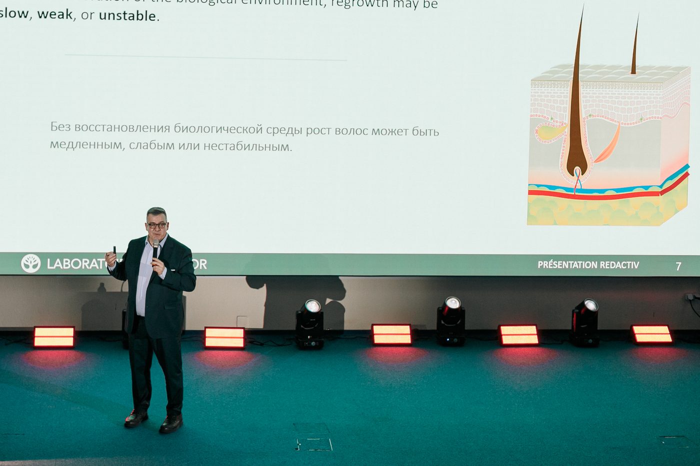 Stéphane PAULET před diagramem vlasového folikulu, který vysvětluje, že bez obnovení biologického prostředí může být opětovný růst pomalý, slabý nebo nestabilní