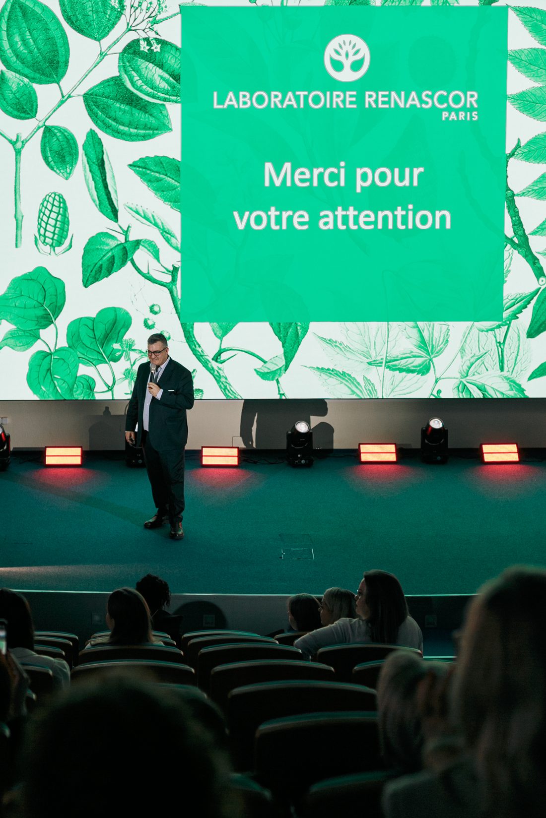 Stéphane PAULET na pódiu na TRIHOFEST 2026 v Minsku, plátno Laboratoire RENASCOR Paris, před publikem profesionálů